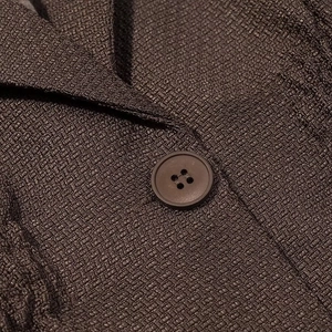 Close-up of a brown textured blazer showing a round button and fabric details
