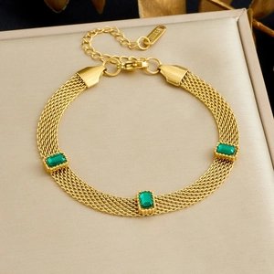 Bracelet en maille d'acier doré avec cristaux vert émeraude sur fond de satin
