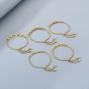 Detail of five adjustable gold-plated stainless steel pull-string bracelets in various styles