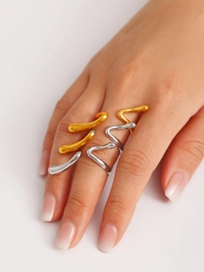 Close-up of stacked wave-shaped gold and silver stainless steel rings on a hand