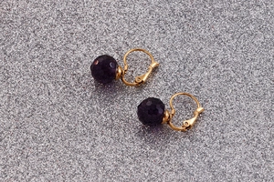 Macro detail of 10mm faceted dark purple crystal drop earrings with golden hooks