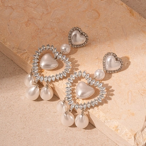 Macro shot of silver pearl heart drop earrings featuring sparkling marquise rhinestones