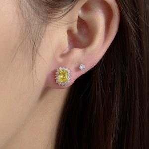 Vintage gold square emerald stud earrings with halo diamonds worn by a model
