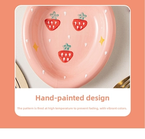Close-up of a pink ceramic plate featuring hand-painted strawberry patterns and a glossy finish