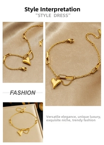 Detail of gold heart pendant bracelet with asymmetric chain and tassel detail