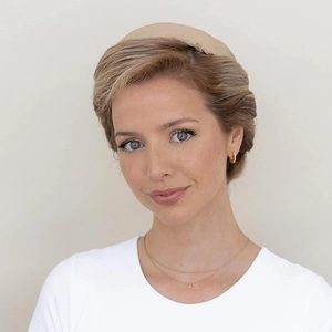 Close-up of model wearing a beige fabric headband with gold layered crescent moon necklace