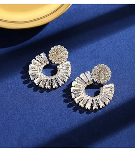 Detailed close-up of radiant gold earrings with sparkling zircon crystals on dark blue background