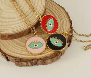 Detailed shot of gold Evil Eye pendants in red, pink, and black on a rustic wood base