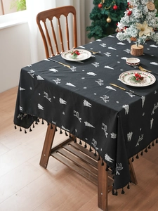 Christmas tablecloth detail with white reindeer patterns and black decorative tassels