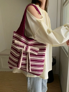 Detail of purple striped knitted tote bag with a large decorative bow on model