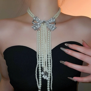 Détail d'un collier de perles double épaisseur avec nœud en strass et longues franges