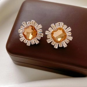 Détail de boucles d'oreilles vintage dorées avec pierre ambre sur écrin en cuir