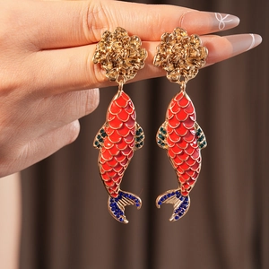 Macro detail of vintage gold flower earrings with red and blue koi fish pendants