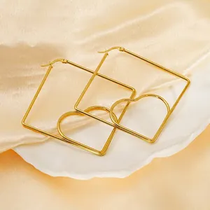Exaggerated gold heart earrings with square frame design on white plate and silk