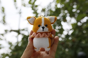 Close-up of handmade crochet Corgi dog keychain with pink scarf and golden ring hook