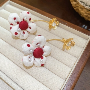 Detailed view of red polka dot fabric flower earrings with pearls and gold ear hooks