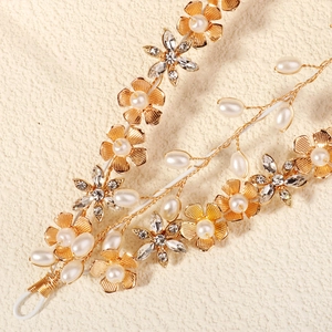 Macro detail of handmade bridal headband with gold petals, rhinestones and white pearls
