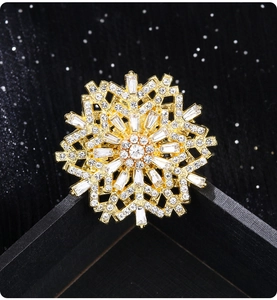 Close-up of gold snowflake brooch with sparkling rhinestones on black gift box