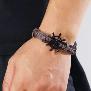 Men's vintage braided brown leather bracelet featuring a black metal helm anchor charm
