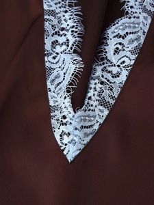 Détail du col en V avec dentelle de cils blanche sur tissu satiné marron foncé