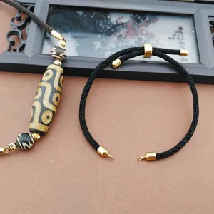 Macro detail of black braided bracelet with Dzi bead and 20cm adjustable gold clasp
