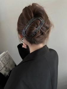 Vue détaillée de la pince à cheveux ovale grise translucide sur une coiffure relevée