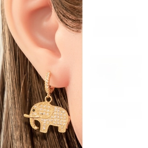 Détail d'une boucle d'oreille pendante éléphant dorée sertie de zircons cubiques brillants