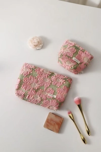 Detail of high-capacity pink floral jacquard cosmetic bags with 3D daisy pattern texture