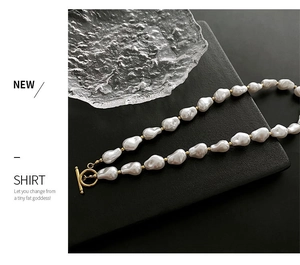 Detailed view of Baroque pearl necklace with golden OT clasp on a black textured background