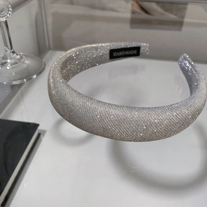 Macro detail of a silver glitter padded headband featuring a handmade black fabric label