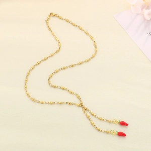 Close-up of golden beaded chain necklace with two glossy red chili pepper pendants