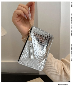 Close-up of silver crocodile pattern clutch with elegant fringe tassel and gold chain