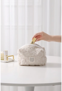 Detail showing hand placing lipstick into cream corduroy lace cosmetic storage bag