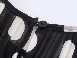 Close-up of neckline with black and white polka dot pattern and pleated texture on chiffon