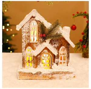 Close-up of wooden Christmas house with LED lights, artificial snow and pine needle detail