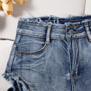 Detalle de pantalones cortos vaqueros de tiro alto con bordes deshilachados y lavado azul