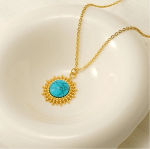 Close-up of 18K gold stainless steel necklace with turquoise star pendant on white ceramic