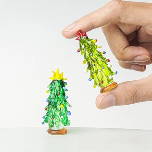 Close-up of a tiny glass Christmas tree held by hand to show its miniature scale