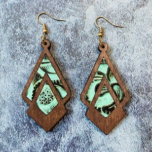 Detail of bohemian geometric wood and turquoise leather earrings with floral patterns