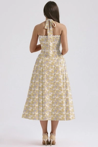 Detail of yellow floral halter dress showing backless design and white lace trim