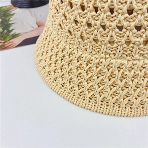 Detailed close-up of beige hollow knit straw hat showing intricate crochet pattern