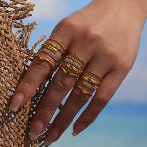 Bohemian gold ring set with colorful zircons worn by model on summer beach background