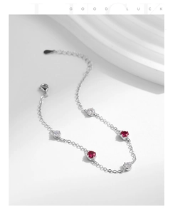 Detail of silver chain bracelet with ruby red and white round stones and lobster clasp