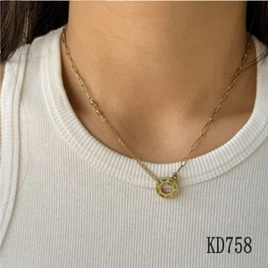 Collier doré avec pendentif donut en émail vert porté sur un modèle en haut blanc