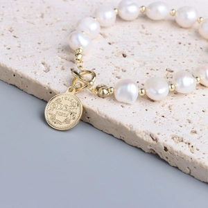 Dettaglio del bracciale con perle barocche d'acqua dolce, ciondolo a moneta e chiusura a T
