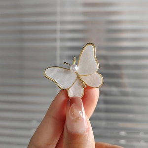 Elegant gold butterfly brooch with mother of pearl wings and a central pearl detail