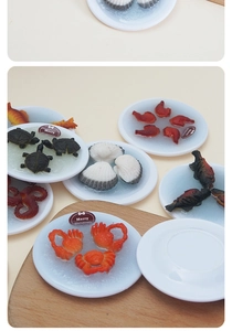 Miniatuur zeevruchten set met feestelijke krab en vis bedeltjes op witte bordjes
