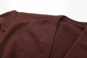 Detailed view of dark brown knitwear stitching and premium gold metal button texture