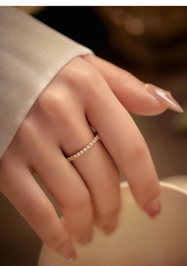Detail of delicate gold paved diamond ring worn on finger for elegant stacking style