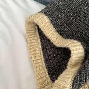 Detail of grey knitted balaclava with beige ribbed edging and thick wool texture